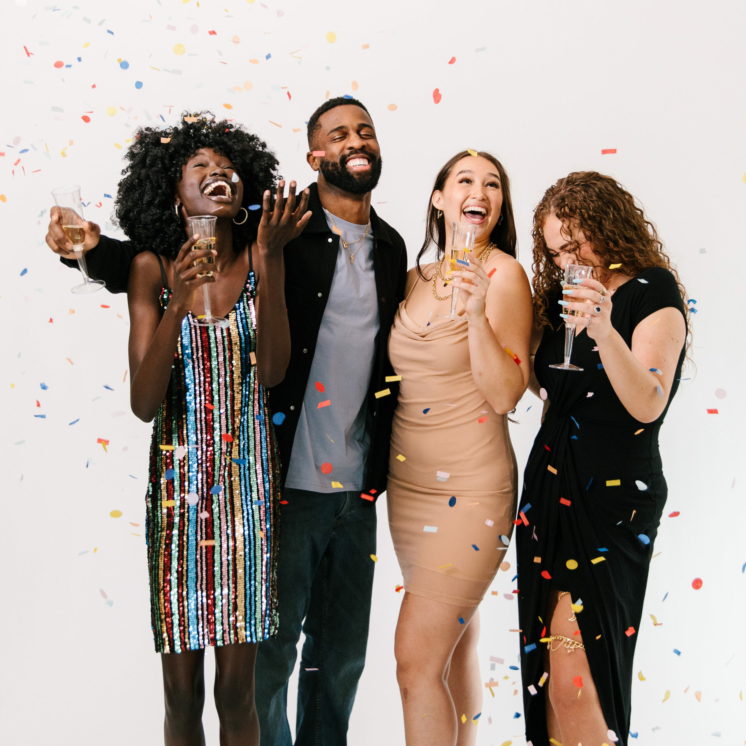 three women and a man celebrating graduation with confetti in the air