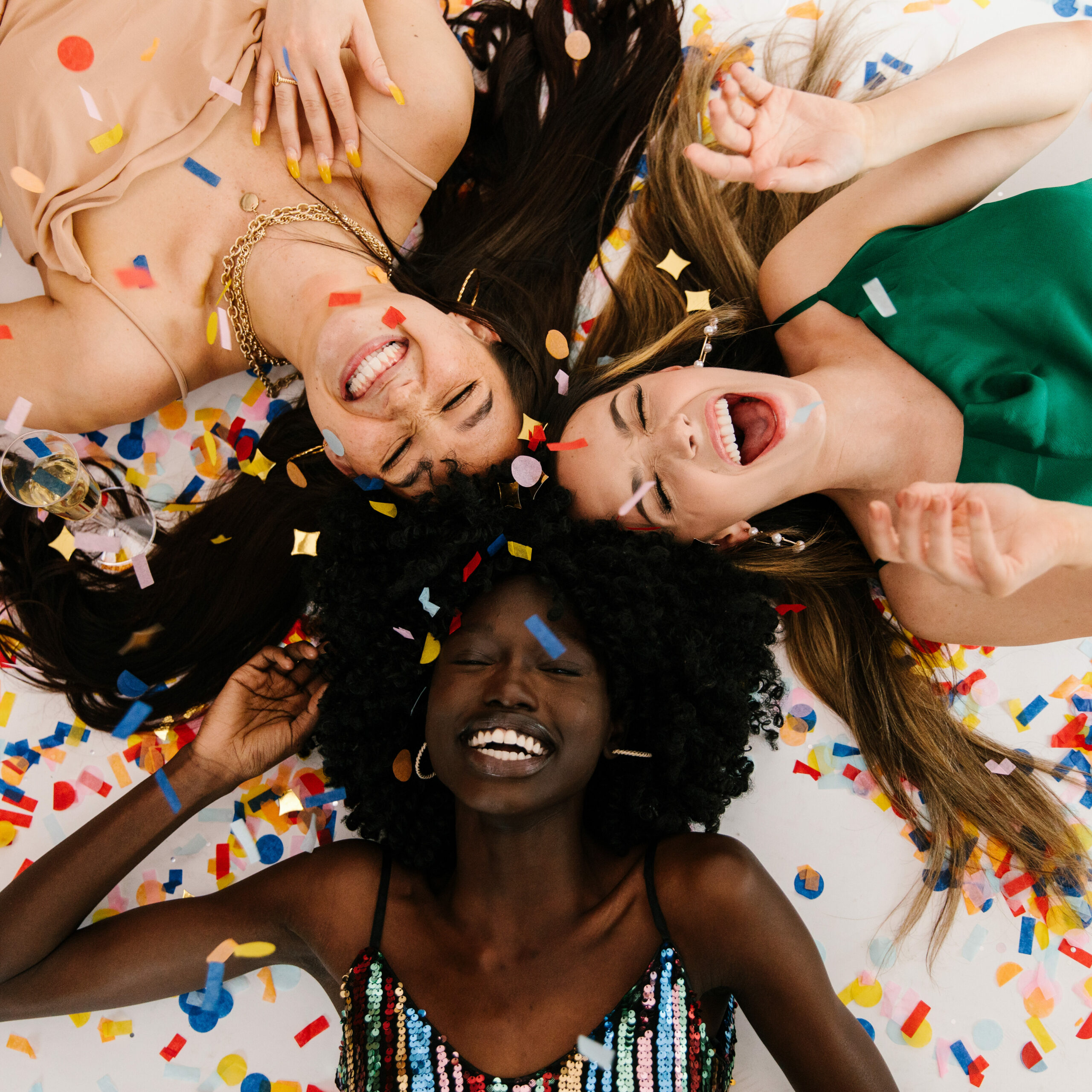 three women laying on the ground with confetti